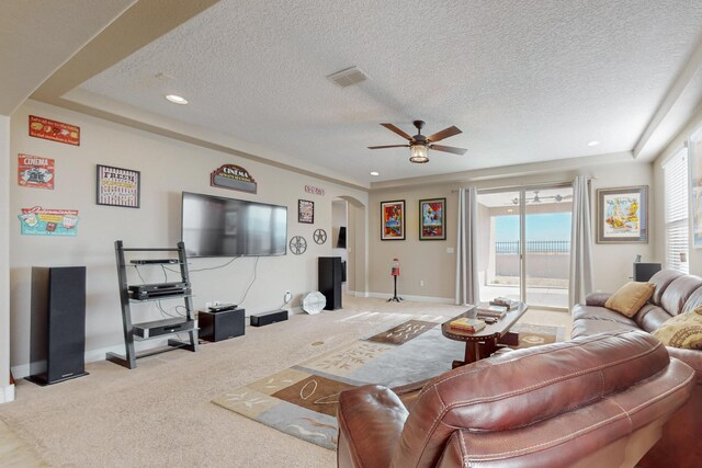 carpeted living room featuring ceiling fan and a textured ceiling