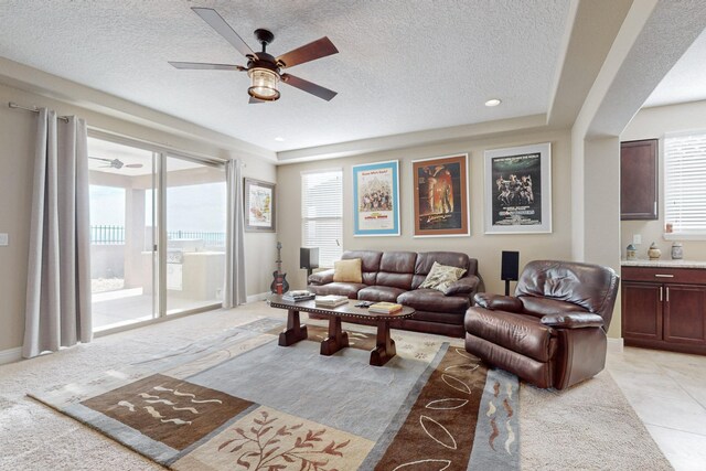 living room featuring light tile patterned flooring, ceiling fan, and a textured ceiling