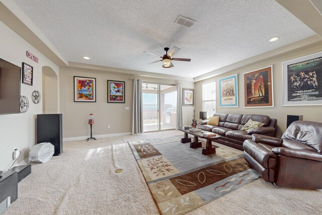 living room featuring carpet flooring, a textured ceiling, and ceiling fan