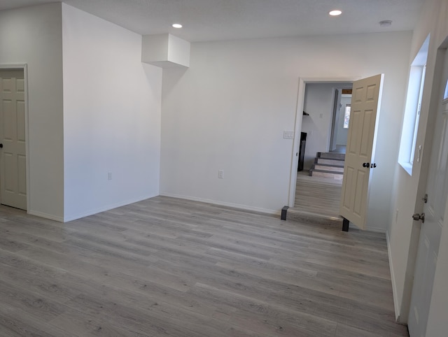 unfurnished room featuring stairs, recessed lighting, wood finished floors, and baseboards