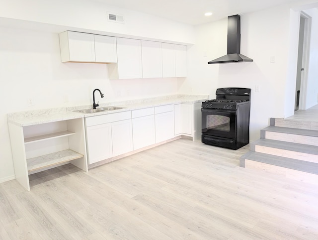 140 65th St NW, Albuquerque, NM 87105 - kitchen featuring black gas range oven, wall chimney exhaust hood, light wood finished floors, white cabinets, and a sink