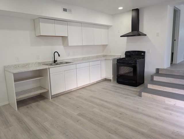 kitchen with light wood finished floors, visible vents, black gas stove, and wall chimney range hood