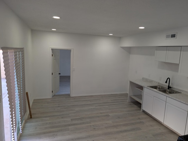 kitchen featuring light wood finished floors, visible vents, a sink, white cabinets, and open shelves