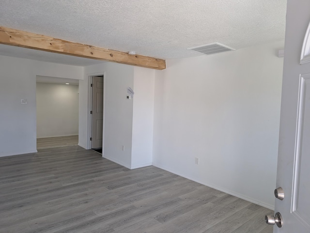 spare room featuring visible vents, wood finished floors, baseboards, and a textured ceiling