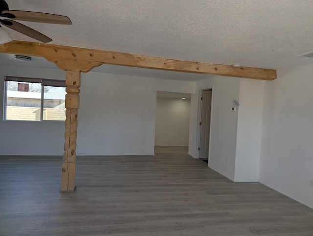 spare room featuring ceiling fan, wood-type flooring, beamed ceiling, and a textured ceiling