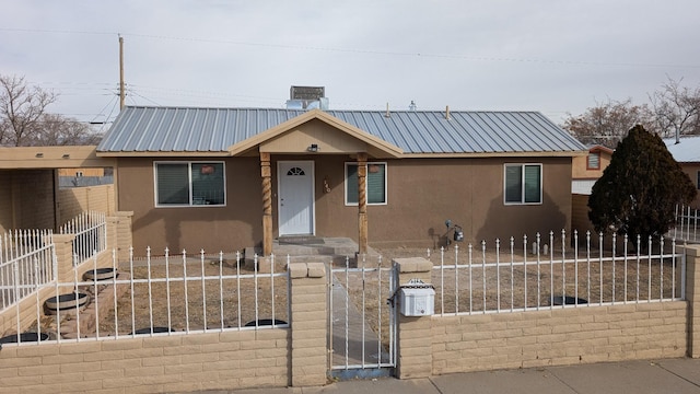 view of front of house featuring stucco siding, metal roof, and a fenced front yard