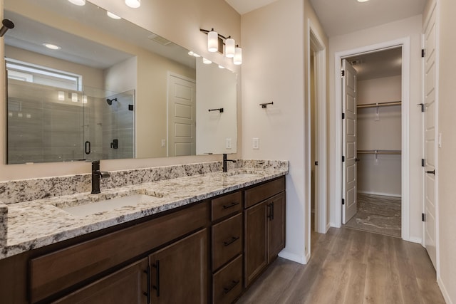 bathroom with hardwood / wood-style flooring, vanity, and walk in shower