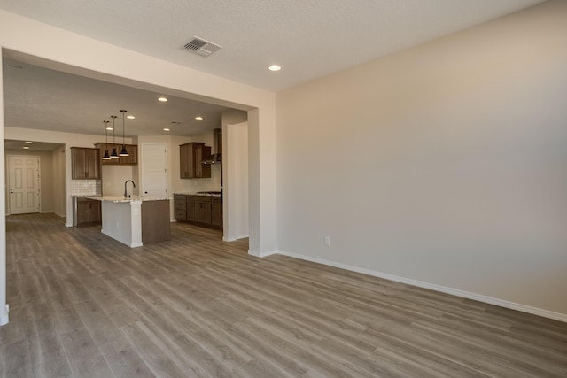 unfurnished living room featuring dark wood-type flooring, sink, and a textured ceiling