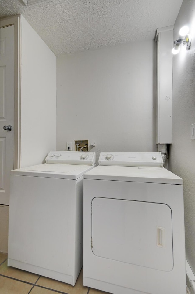 laundry room with light tile patterned floors, a textured ceiling, and washing machine and clothes dryer