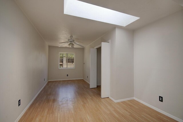 unfurnished room featuring light wood-type flooring, a skylight, and ceiling fan