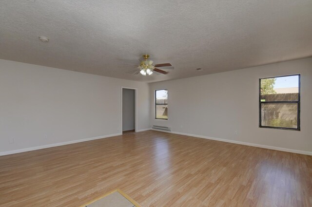 unfurnished room with a textured ceiling, light hardwood / wood-style floors, ceiling fan, and a baseboard heating unit