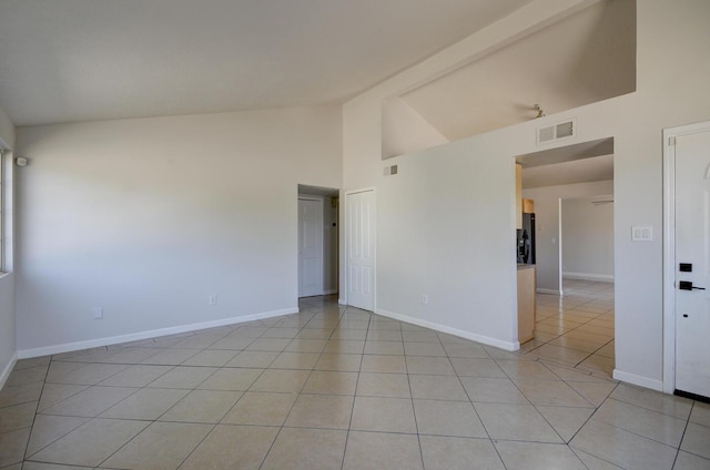 tiled empty room featuring high vaulted ceiling