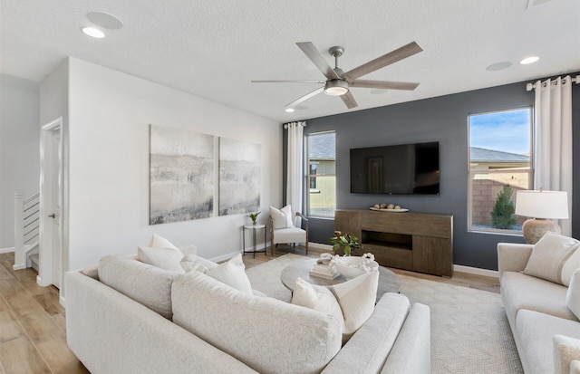 living room with ceiling fan, a healthy amount of sunlight, a textured ceiling, and light hardwood / wood-style flooring