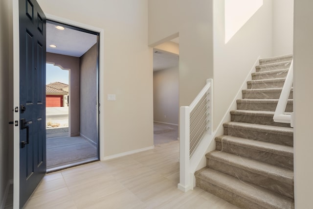 foyer entrance featuring stairway and baseboards