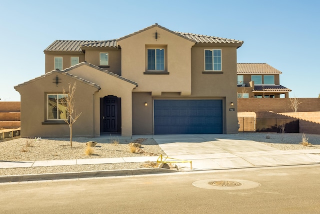 mediterranean / spanish-style home featuring a tile roof, stucco siding, fence, a garage, and driveway