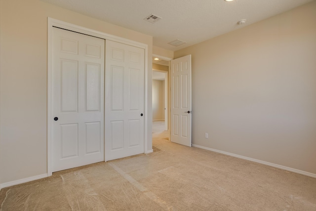 unfurnished bedroom with light carpet, baseboards, visible vents, and a closet