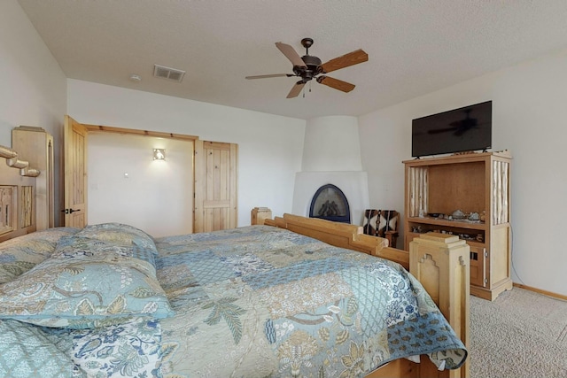 carpeted bedroom with ceiling fan and a textured ceiling