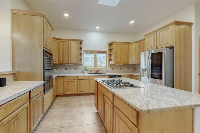 kitchen featuring sink, a center island, light brown cabinetry, light tile patterned floors, and appliances with stainless steel finishes