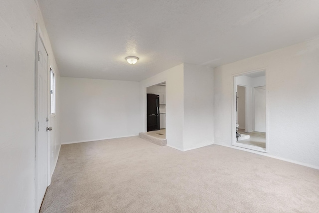 spare room with a textured ceiling and light carpet