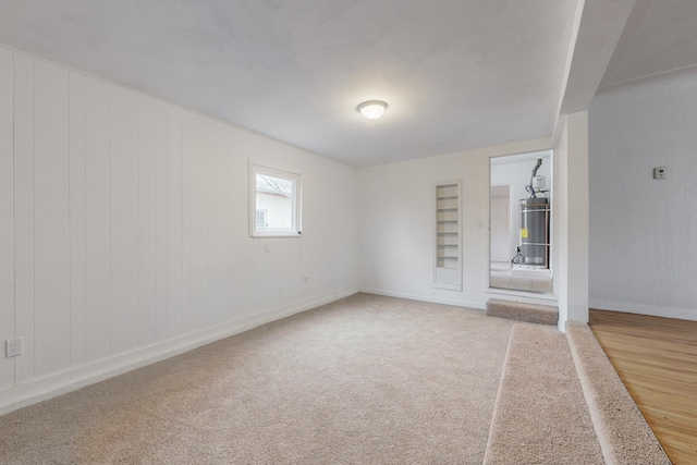 carpeted spare room featuring built in features and water heater