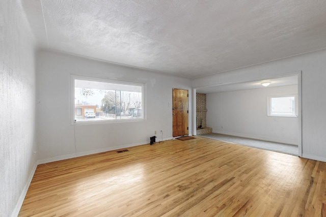 spare room with a textured ceiling and light hardwood / wood-style flooring