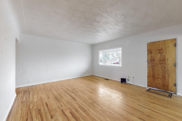 spare room featuring light wood-type flooring and a textured ceiling