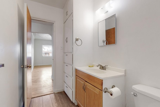 bathroom with hardwood / wood-style floors, vanity, and toilet