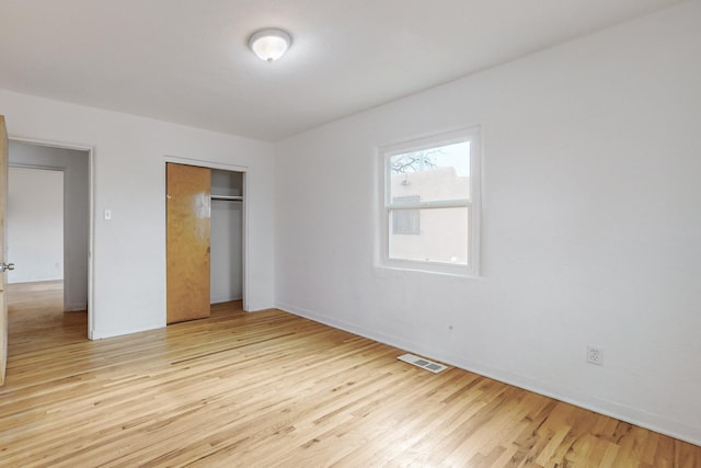 unfurnished bedroom with a closet and light wood-type flooring