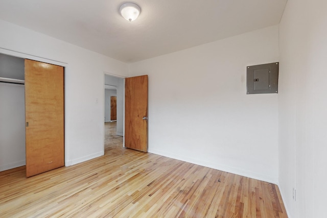 unfurnished bedroom with electric panel, a closet, and light hardwood / wood-style floors