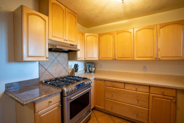 kitchen with high end stove, backsplash, light tile patterned flooring, and a textured ceiling