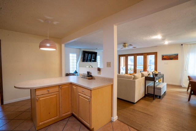 kitchen with kitchen peninsula, ceiling fan, light brown cabinets, light tile patterned floors, and decorative light fixtures