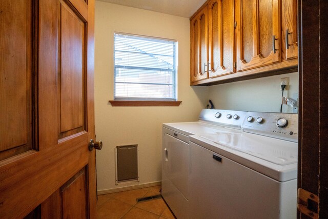 laundry area with washer and dryer, light tile patterned floors, and cabinets