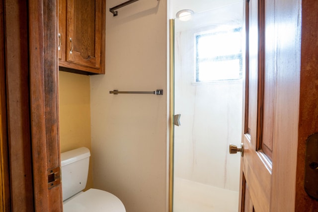 bathroom featuring toilet and a shower with door