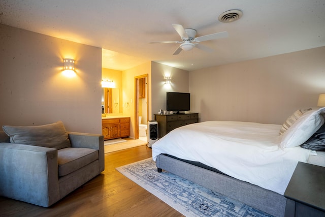 bedroom with wood-type flooring, ensuite bathroom, and ceiling fan