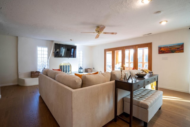 living room featuring hardwood / wood-style flooring, ceiling fan, and a textured ceiling