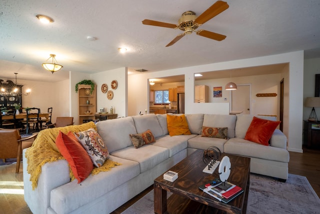 living room with hardwood / wood-style floors, ceiling fan with notable chandelier, and a textured ceiling