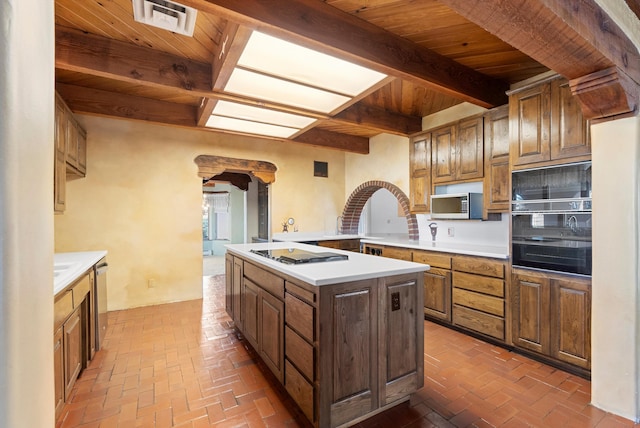 kitchen with wooden ceiling, beam ceiling, appliances with stainless steel finishes, a kitchen island, and kitchen peninsula