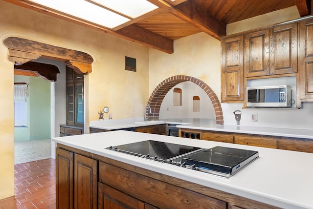 kitchen with beamed ceiling, cooktop, wood ceiling, and sink