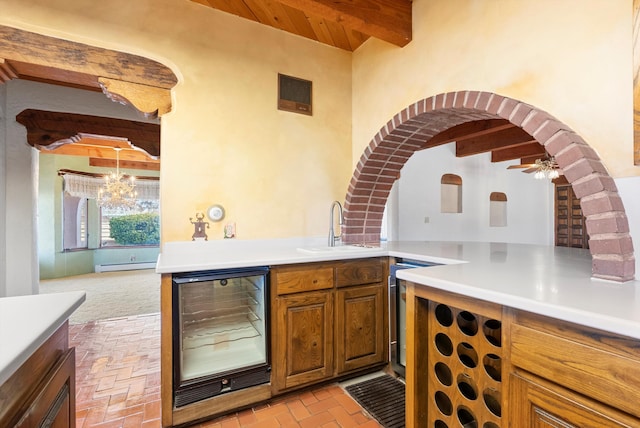 kitchen featuring sink, beverage cooler, beamed ceiling, a baseboard heating unit, and ceiling fan with notable chandelier