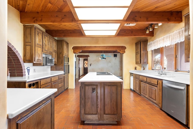 kitchen with beam ceiling, a kitchen island, sink, and appliances with stainless steel finishes