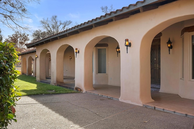 entrance to property featuring a lawn and a patio