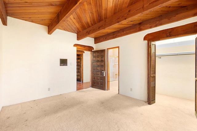 unfurnished bedroom featuring beam ceiling, wooden ceiling, ensuite bathroom, a closet, and carpet