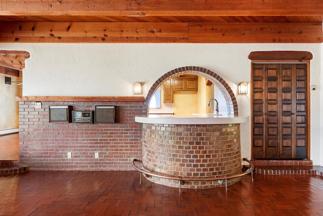 bar with beam ceiling, sink, wood ceiling, and brick wall