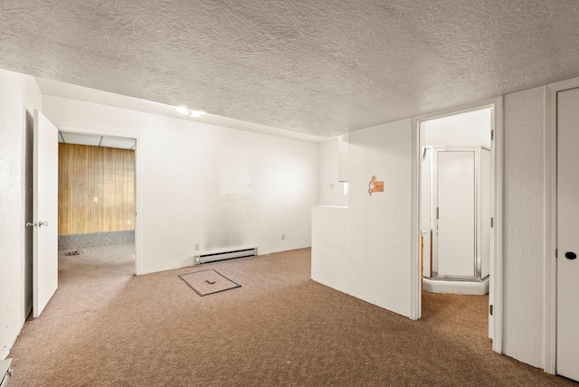 empty room with a textured ceiling, wood walls, carpet floors, and baseboard heating