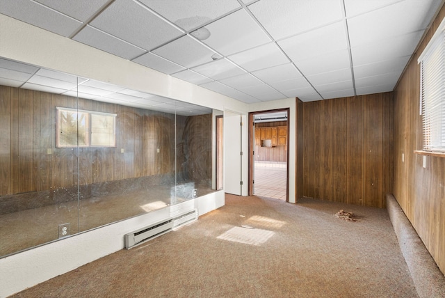 basement featuring wooden walls and a baseboard heating unit