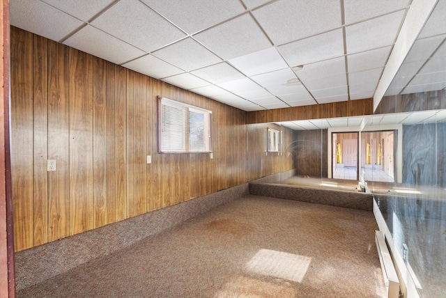 corridor featuring carpet flooring, baseboard heating, and wood walls