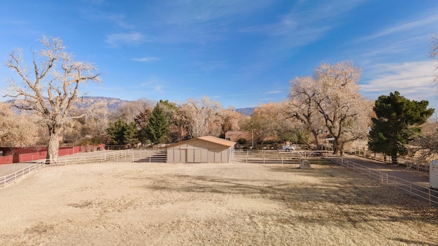 view of yard with a mountain view, a rural view, and an outbuilding