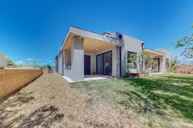 back of house with a patio and a lawn