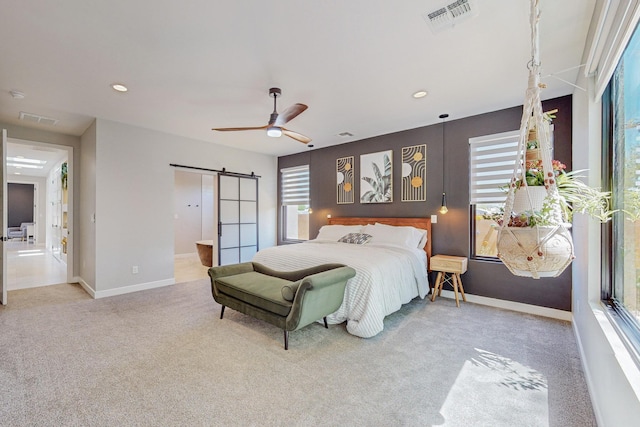 bedroom featuring a barn door, ceiling fan, carpet floors, and ensuite bathroom