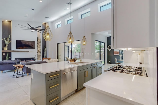 kitchen featuring a center island with sink, hanging light fixtures, sink, gray cabinets, and appliances with stainless steel finishes